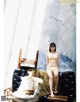 A woman in a yellow bikini sitting on a couch.