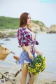 A woman standing next to a bike holding a bunch of flowers.