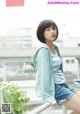 A woman sitting on top of a railing next to a building.