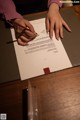 A woman signing a document on a table.