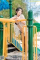 A woman in a white shirt and black bikini posing on a playground.