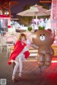 A woman sitting on a bench next to a giant teddy bear.