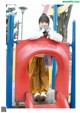 A young girl is standing on a red slide.